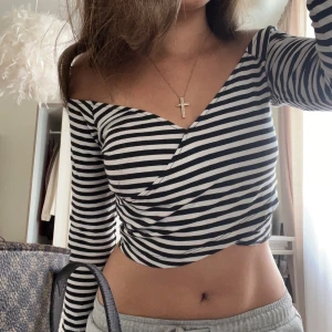 Randig omlottopp från Bik Bok - Säljer en snygg randig omlottopp från Bik Bok i svart och vitt. Toppen har en croppad design med långa ärmar.💞❤️