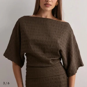 Brun långklänning med kortärmad topp - Elegant brun topp från Nelly. Helt nytt skick har aldrig använts. Stretchiga material med vida ärmar den är även figur anpassad i midjad. Sitter väldigt fint. Köpte fel storlek och därför sälja den. Om du vill veta mer eller ha en bild på kan du skriva till mig☺️