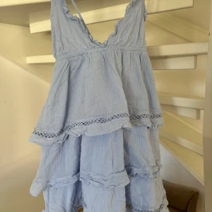 Ljusblå klänning med volanger storlek S - Lljusblå klänning med volanger och spetsdetaljer från Gina Tricot. Den har smala axelband och en luftig passform, perfekt för varma dagar. Passar mig som är 164 cm.