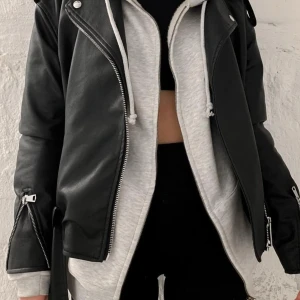 Svart översizedskinnjacka med dragkedja - ANVÄND FÅTAL GÅNGER!Snygg svart skinnjacka med dragkedja och bälte i midjan. Jackan har långa ärmar och flera dragkedjedetaljer som ger en cool look. Perfekt för att ge din outfit en edgy touch🪩