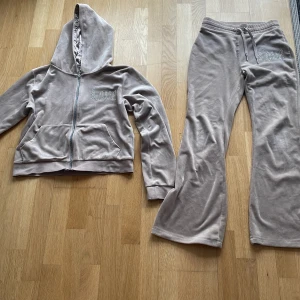 Beige hoodie och byxor från Lindex - Säljer ett mysigt set med hoodie och byxor från Lindex i beige färg. Hoodien har dragkedja och luvan är perfekt för kyliga dagar. Både hoodie och byxor har texten 'Love' i glittriga stenar.🤍🤍