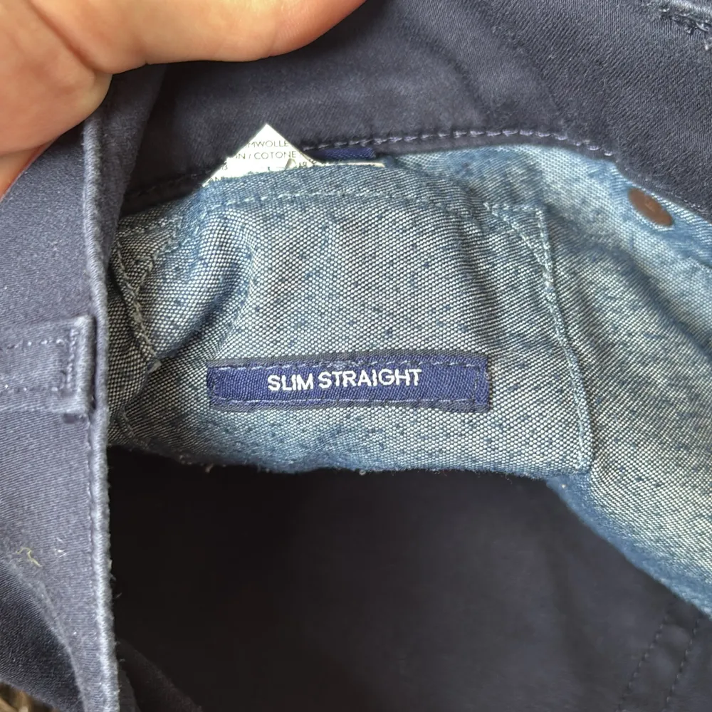 Säljer ett par mörkblå byxor från Gant i modellen slim straight. Byxorna har en klassisk design med dragkedja och knappar. Perfekta för en stilren look. W33/L32. Farkut & Housut.