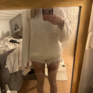 Vita jeansshorts  - Säljer ett par vita jeansshorts med fransiga kanter. Shortsen har en klassisk femficksdesign och knappar framtill. Perfekta för sommardagar! 🌞( högmodjade)