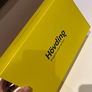 Svart airbag-hjälm från Hövding, cykelhjälm  - Säljer en svart airbag-hjälm från Hövding, perfekt för cyklister i stadsmiljö. Hjälmen aktiveras automatiskt vid olycka och ger ett säkert skydd för huvudet. Den är lätt att bära runt halsen och har en diskret design. Använd uppskattningsvis 30 timmar. I mycket gott skick. Säljs i befintligt skick. Alla till tillbehör på bilderna följer med köpet. 