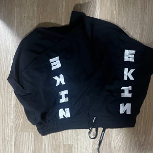 Svarta shorts med tryck - Snygga svarta shorts med ett coolt vitt tryck längs sidan som kan användas vardaglig men även badshorts. De har en elastisk midja med dragsko för justerbar passform. Perfekta för en avslappnad stil.