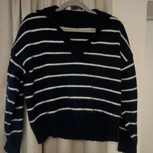 Svart och blå randig stickad tröja - Säljer en mysig stickad tröja. Tröjan har en v-ringad design och långa ärmar. Storlek står ej men sitter som s:)