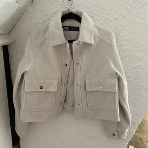 Beige jacka från Zara - Säljer en stilren beige jacka från Zara med knappar framtill och stora fickor. Jackan har en klassisk krage och är långärmad, perfekt för höst och vår. Den är tillverkad i ett mjukt material som ger en bekväm passform. Lånade bilder!!💓
