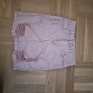 Rosa jeanskjol med slitningar - Cool jeanskjol i en fin rosa färg. Väldigt liten, midjemåttet är 29 och längden 40. Går nog att göra den snyggare genom att typ klippa den kortare om man vill det!🩷🩷