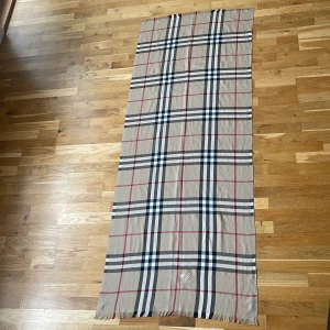 Beige rutig halsduk - Snygg beige halsduk med klassiskt rutmönster i svart, vitt och rött. Perfekt för att ge en stilren touch till din outfit. Märket är synligt i ena hörnet och fransar pryder kanterna. Vid mer frågor eller intresse skriv i dm. Går ner i pris vid snabbaffär!!!