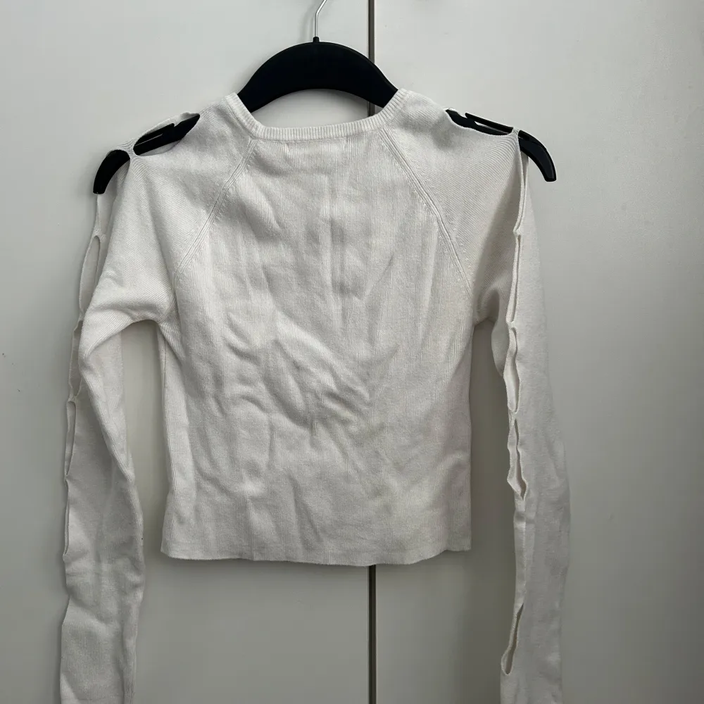 Säljer en vit tröja med unika cut-out detaljer längs ärmarna. Tröjan har en tight passform och är tillverkad i ett mjukt material som ger en bekväm känsla☺️. Neuletakit & Villapaidat.