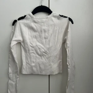 Vit tröja med cut-out detaljer - Säljer en vit tröja med unika cut-out detaljer längs ärmarna. Tröjan har en tight passform och är tillverkad i ett mjukt material som ger en bekväm känsla☺️