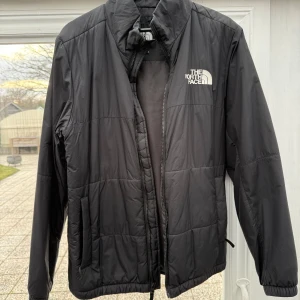 Svart jacka från The North Face - Säljer en stilren svart jacka från The North Face. Perfekt för kyligare dagar med sin lätta och bekväma design. Jackan är tryckt på bröstet och ryggen.
