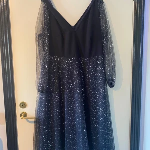 Svart glittrig klänning från Shein - Säljer en elegant svart klänning från Shein med glittrigt mönster. Klänningen har långa ärmar i transparent material och en v-ringad design. Perfekt för festliga tillfällen! ✨