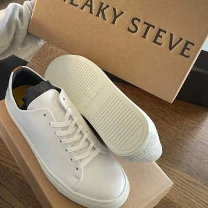 Vita sneakers från Sneaky Steve - Snygga vita sneakers från Sneaky Steve i skinn. De har en klassisk design med snörning och en rund tå. Perfekta för studenten. De är helt nya endast uppackade för bild. Nypris 1499kr. 