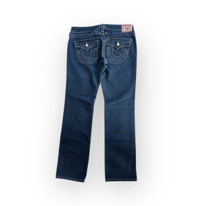 True Religion disco billy x Swarowski  - Storlek W28, passar S. Snygga blå jeans med broderade detaljer på bakfickorna och en klassisk femficksdesign. De har en normal passform och är perfekta för en avslappnad stil. Märkeslappen på baksidan ger en extra touch av stil. Inga tydliga defekter. Midja 39 innerben 73