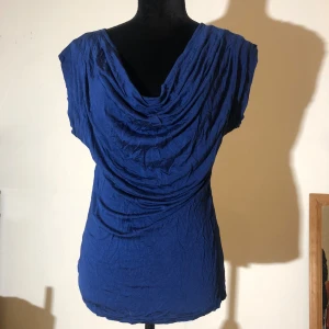 Marinblå t-shirt  - T-shirt från Kappahl med ”droppande” u-ringning. Sista bilden är mest likvärdig med färgen i verkligheten. Längd ca 70cm.