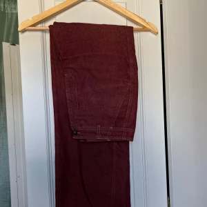 Röda jeans - Ett par röda jeans, köpta på betong retro för ex antal år sedan. Märket är okänt. Storlek 38, 38 cm tvärsöver midjan. 73 cm innerbenslängd. 27 cm från grenen till midjan.