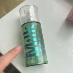 Hydro Grip Primer från Milk Makeup - Hydro Grip Primer från Milk Makeup i en genomskinlig flaska med pump. Den har en grönaktig ton och är känd för att ge en återfuktande och långvarig bas för smink.
