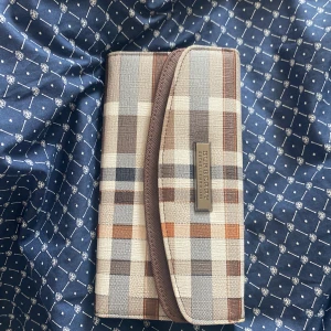 Rutig plånbok från Burberry - Snygg rutig plånbok från Burberry i bruna och beige toner. Plånboken har flera kortfack och en praktisk dragkedja inuti. Perfekt för att hålla ordning på dina kort och kontanter.