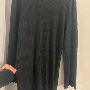 Svart ribbad klänning  - Säljer en stilren svart ribbad klänning med långa ärmar. Perfekt för en minimalistisk look.