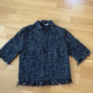 Tröja  - Svart kortsätmad tröja med detaljer vid armarna och nedre delen av tröjan! Dragkedja bak i nacken! Knappt använd 