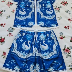 Blå mönstrade sett från Casablanca - Snygga blå sett från Casablanca med ett unikt mönster av svanar och dekorativa element. Shortsen har en bekväm passform med snörning i midjan för justerbarhet. Perfekta för en stilfull och avslappnad look.