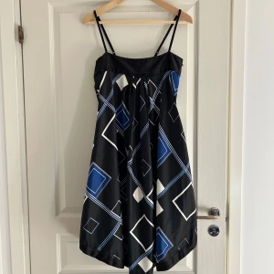 Svart klänning med geometriskt mönster - Snygg svart klänning med blå och vita geometriska mönster. Axelbandslös design med smala axelband och en luftig passform. Min absoluta favorit som är min mammas gamla, men tyvärr är den liten till mig, kan inte helt stänga dragkedjan på sidan. 