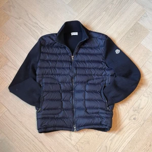 Moncler cardigan - Fits like M. Säljer en snygg mörkblå quiltad jacka från Moncler. Jackan har en dragkedja framtill och långa ärmar. Perfekt för kyligare dagar med sin stilrena design och varma material.