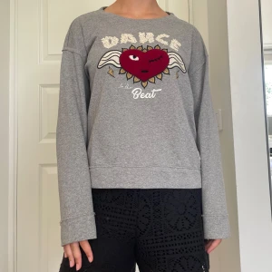 Grå sweatshirt Odd Molly med hjärta - Grå sweatshirt från Odd Molly med broderat rött hjärta med vingar och texten 'Dance to the Beat' framtill. Tröjan har rund hals, långa ärmar och är i mjuk bomullsblandning. Perfekt för dig som gillar coola detaljer och skön passform. Skriv om du undrar något, kolla min profil innan du trycker på köp nu💗💗