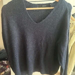 Mörkblå stickad tröja Vero Moda - Mysig mörkblå stickad tröja från Vero Moda med v-ringning och lång ärm. Tröjan har en enkel, ribbad struktur och är perfekt för lager-på-lager. Passar dig som gillar en klassisk och chill stil.