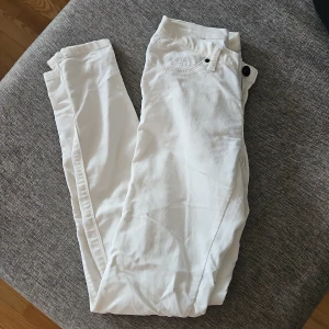 Vita skinny jeans - Snygga vita skinny jeans med klassisk femficksdesign och smal passform. Byxorna har midja med knapp och dragkedja, perfekta till sneakers eller boots. Fräscha och stilrena för en clean look.