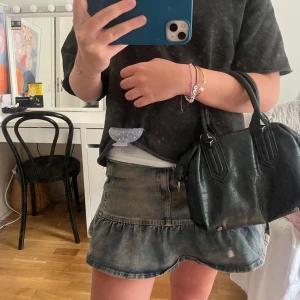 Svart handväska i croco-look från Zara - Säljer en svart handväska från Zara med croco-mönstrad yta och coola silverdetaljer vid handtagen. Väskan har två rejäla handtag och dragkedja upptill. Perfekt storlek för mobilen, plånboken och lite smink. Snygg och stilren att bära till alla outfits.