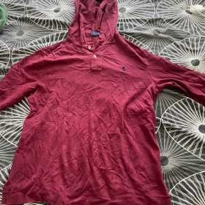 Vinröd hoodie från Polo Ralph Lauren  - Säljer en vinröd tunn hoodie från Polo Ralph Lauren storlek (m)med klassisk huva knappar vid halsen. Tröjan har lång ärm och är tillverkad i mjuk bomull
