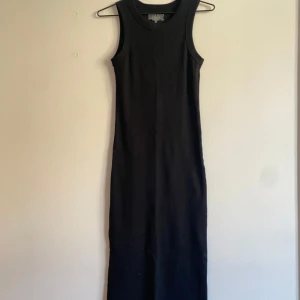 Svart långklänning Bread & Boxers - En svart, ribbad långklänning från Bread & Boxers i storlek XS. Klänningen är ärmlös med rund halsringning och har en slim passform. Tillverkad i mjuk bomull med lite stretch för extra komfort.  för Ger clean och stilren look.
