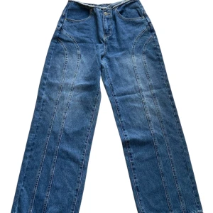 Blå wide jeans med  sömmar - Säljer ett par blå jeans med breda ben och snygga dekorativa sömmar längs framsidan. Klassisk femficksmodell med raka bakfickor och normal midja. Jeansen är 96 cm långa 