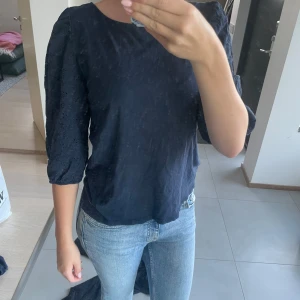 Mörkblå blus från Hampton Republic - Supersöt mörkblå blus från Hampton Republic i storlek XS. Blusen har broderade detaljer och trekvartsärmar med lätt puff. Materialet är bomull och känns luftigt och skönt. Perfekt till jeans eller kjol för en chill men ändå uppklädd look.