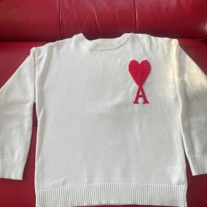 Vit stickad tröja Ami med rött hjärta - Vit stickad tröja från Ami Alexandre Mattiussi med ribbade muddar och nederkant. Storlek S men passar M om frågan om mer bilder dyker upp så kan ni bara fråga. Priset kan också negotieras (köpte den för 1700 och den är riktig)
