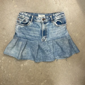 Jeanskjol med volang  - Säljer en blå jeanskjol från Lindex med volang nertill och klassiska fickor bak och fram. 