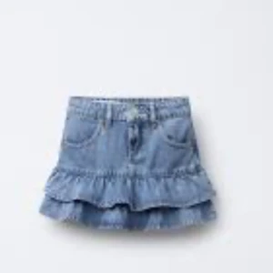 Svart volangkjol från Zara - Supersöt svart kortkjol från Zara med volangkant nertill och resår i midjan. Kjolen har bälteshällor och en enkel, stilren look som passar perfekt till sneakers eller boots. Perfekt för dig som gillar en trendig och enkel stil.