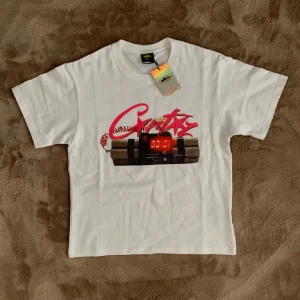 Vit t-shirt NO TIME 4 LUV - Helt ny! Vit t-shirt från Coreiz med tryck av en digital bomb och rosa graffiti-text framtill. Baksidan har stor svart text 'NO TIME 4 LUV'. Klassisk passform och korta ärmar, perfekt för dig som gillar streetwear med attityd. 