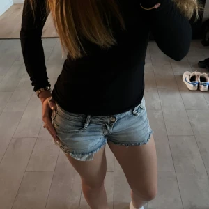 Lågmidjade jeanshorts - Säljer ett par ljusblå jeansshorts i storlek XS. De har fina detaljer på sidorna och är i bra skick💗