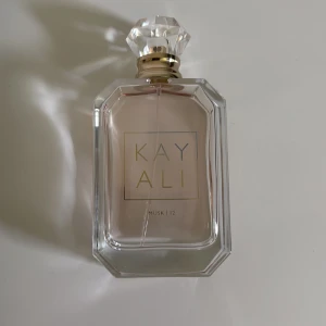 Kayali Musk | 12 Eau de Parfum - Lyxig parfym från Kayali i doften Musk | 12. Flaskan är transparent med en svagt rosa tonad vätska, har en elegant, åttakantig form och ett kristalliknande lock med gulddetaljer. Perfekt för dig som gillar stilrena och exklusiva doftflaskor.