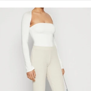 Vit långärmad tubtopp Gina Tricot XS - Supersnygg vit tubtopp från Gina Tricot i storlek XS. Toppen har långa ärmar och axelbandslös design som ger en clean och modern look. Perfekt att styla med höga byxor eller kjol för en trendig vibe.