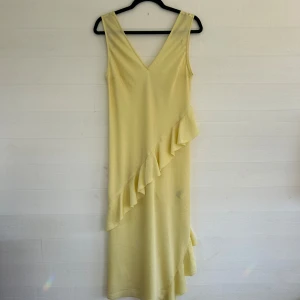 Ljusgul volangklänning - Supersöt ljusgul klänning från H&M med v-ringning och ärmlös design. Klänningen har en snygg volangdetalj som går diagonalt över framsidan och ned längs kjolen. Perfekt för sommarens alla tillfällen! Aldrig använd med lappen kvar!🤩💕
