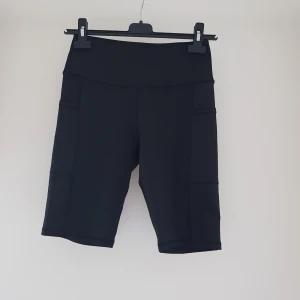 Svarta cykelshorts med fickor från temu strl M - Svarta cykelshorts med hög midja och praktiska sidofickor. De är tillverkade i ett stretchigt syntetmaterial som sitter tight och bekvämt. Perfekta för träning eller när du vill ha en sportig look. Klassisk design utan synliga loggor eller mönster.  Nya så inget att anmärka på