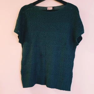 Mörkgrön stickad tröja från lafayette strl L - Snygg mörkgrön stickad tröja från Gina med korta ärmar och rund hals. Tröjan har ett luftigt, virkat mönster och bred ribbad kant nedtill. Perfekt att slänga på sig över ett linne eller t-shirt för en chill look.  Tråddragningar finns annars helt & fint skick