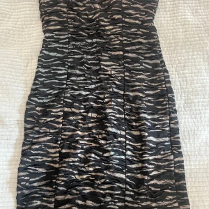Svart och beige axelbandslös klänning - Axelbandslös kort klänning från New Yorker i svart och beige med zebramönster. Klänningen har en tight passform och rynkade detaljer över hela tyget. 📩 Skicka gärna ett meddelande vid frågor eller om du vill ha flera bilder! 🌸😊 📦 Jag skickar snabbt och packar alltid med omsorg!