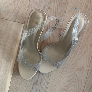 Glittriga klackar Zara - Klackar från Zara med silvriga rhinestones. Skorna har öppen tå, smal hög klack och en rundad form. Storlek 41. Endast använda en gång.