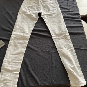 Vita skinny jeans med slitningar - Säljer ett par vita skinny jeans med snygga slitningar framtill. Jeansen har klassisk femficksdesign, dragkedjegylf och smal passform hela vägen ner. Perfekta för dig som gillar en fräsch och trendig look.