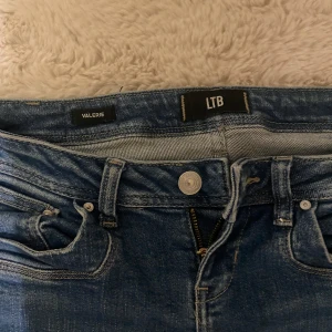 Blå lågmidjade bootcut jeans från LTB - Snygga blå jeans från LTB i modellen Valerie. Jeansen har klassisk femficksdesign, dragkedja och knapp framtill samt bootcut-ben som ger en schysst siluett. Perfekta till sneakers eller boots. Materialet är mjukt denim i bomull. Bra skick! 